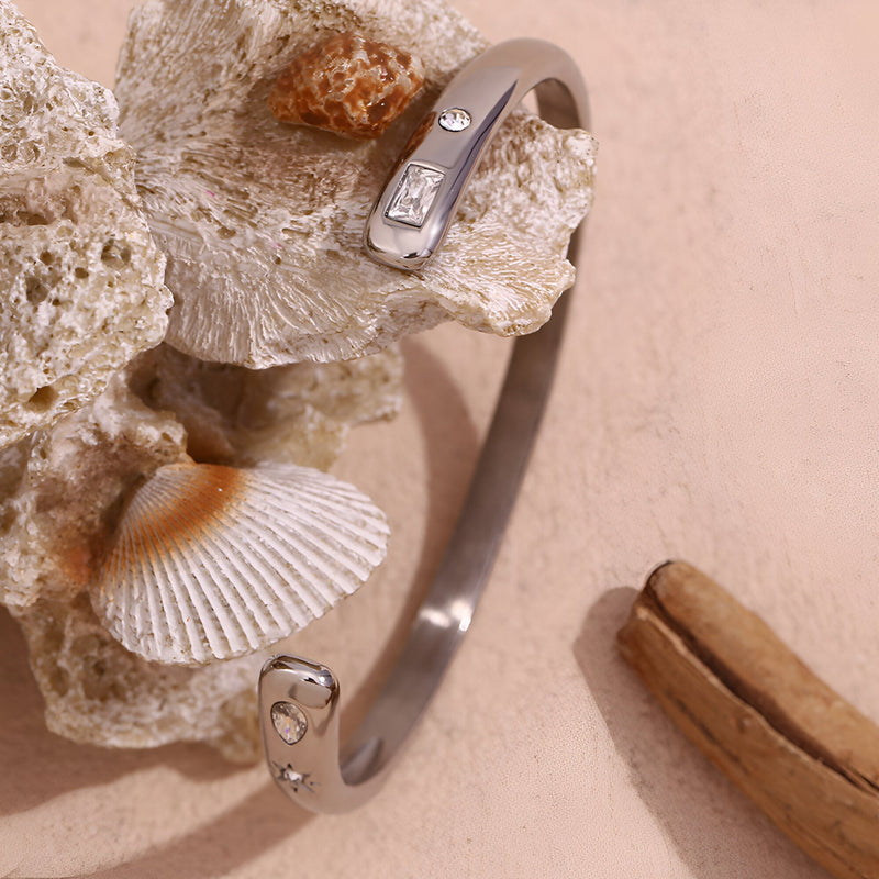 Bracelet jonc fin en acier inoxydable argenté avec motifs astres gravés et strass subtils.