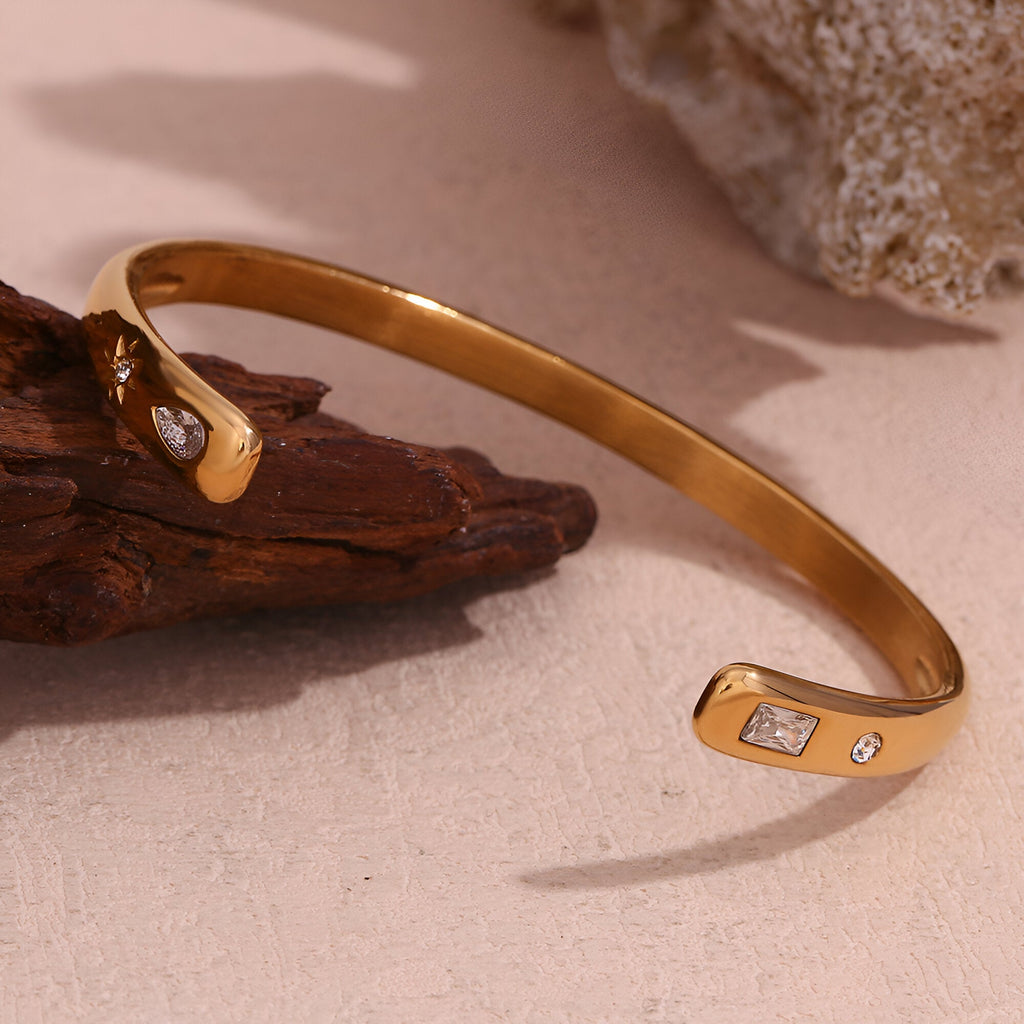 Bracelet jonc Hélios en acier inoxydable doré avec trois petits cristaux brillants.