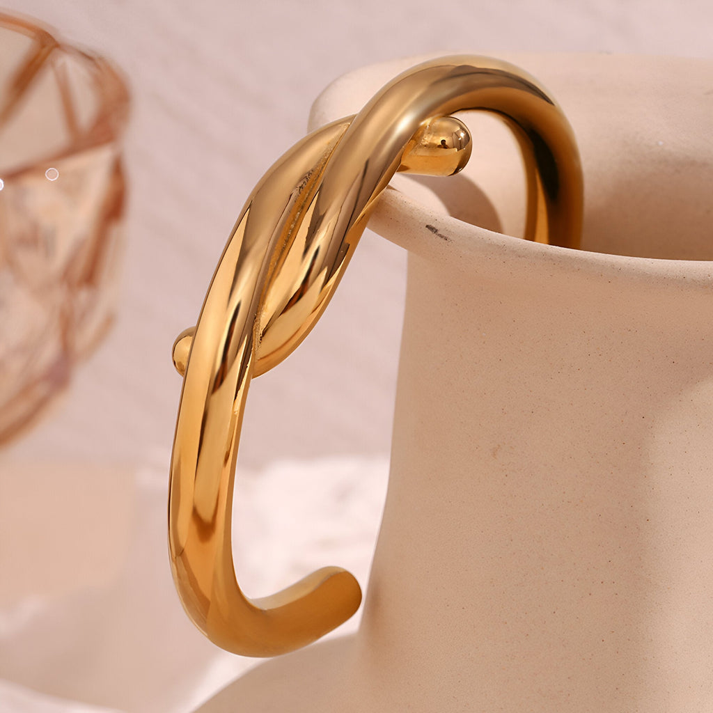 Bracelet jonc en acier inoxydable doré avec design entrelacé élégant.