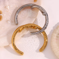 Bracelet jonc entrelacé en acier inoxydable, finition argentée et dorée, texture martelée.