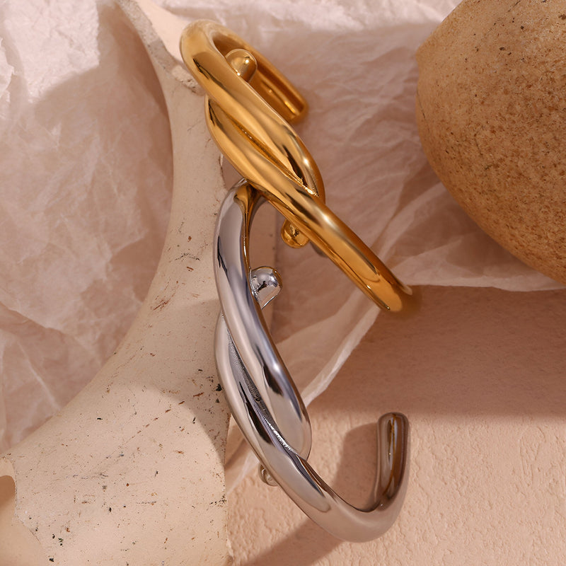 Bracelet jonc entrelacé en acier inoxydable, finition argent et or, design moderne et élégant.