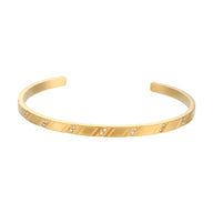 Bracelet jonc doré en acier inoxydable avec motif géométrique et petits cristaux intégrés.