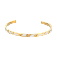 Bracelet jonc en acier inoxydable doré avec motifs géométriques blancs et dorés élégants.
