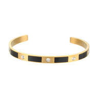 Bracelet jonc doré design géométrique avec rectangles noirs et trois strass brillants.
