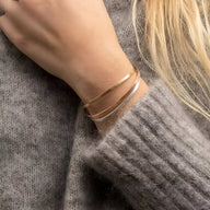 Bracelet jonc fin en acier inoxydable doré, design minimaliste porté sur poignet féminin.