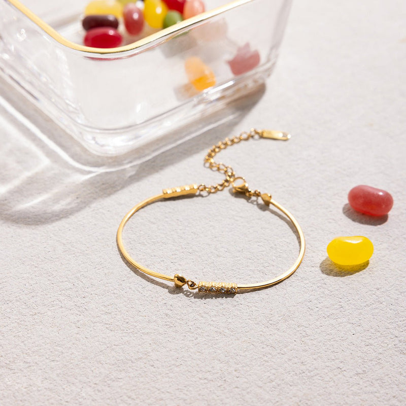 Bracelet jonc doré fin avec chaîne ajustable, cœur orné de petits zircons scintillants et fermoir mousqueton.