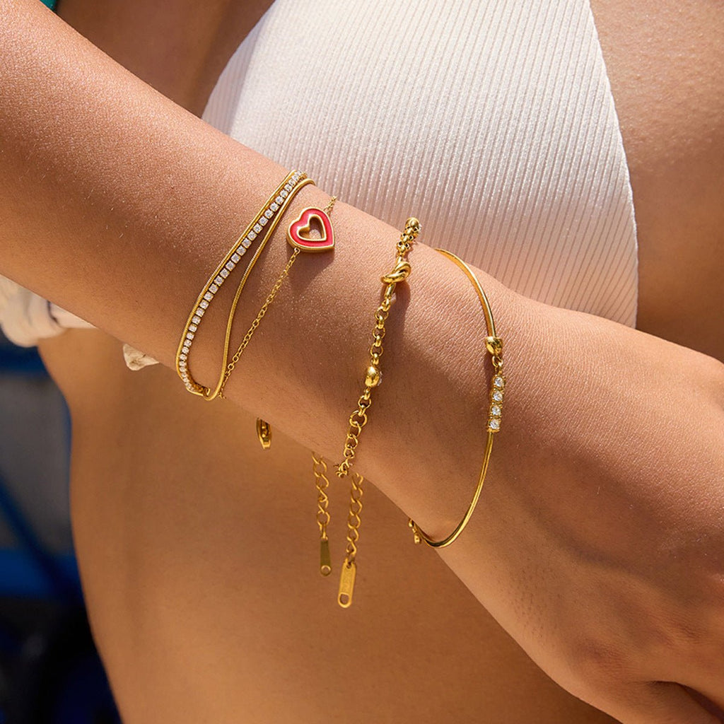 Bracelet jonc doré 18 carats avec cœur rouge et zircons scintillants, ajustable avec fermoir mousqueton.