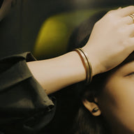 Bracelet jonc double en cuivre or vieilli sur poignet, style antique et élégant.