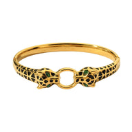 Bracelet jonc doré avec double tête de léopard gravée et yeux verts en pierre.