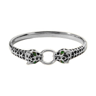 Bracelet jonc argenté double tête de léopard avec yeux verts et anneau central.
