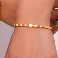 Bracelet jonc fin en acier inoxydable doré avec éclats carrés scintillants, style élégant féminin.