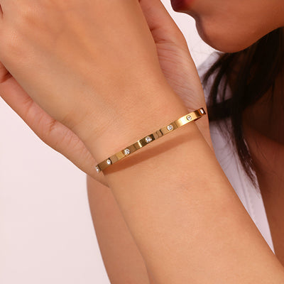Bracelet jonc or en acier inoxydable avec éclats de lumière, design Roshan délicat.