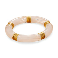 Bracelet jonc en acrylique rose clair avec anneaux dorés élégants.