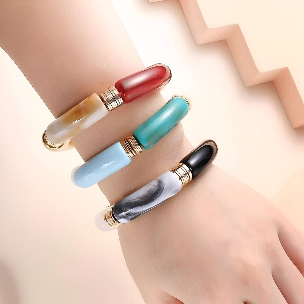 Lot de quatre bracelets joncs en acrylique, couleurs variées et effet marbré, le tout sur une peau claire.