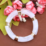 Bracelet jonc Emilia en acrylique blanc translucide avec anneaux dorés élégants.