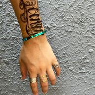 Bracelet jonc fin en acier inoxydable finition arc-en-ciel aux reflets irisés sur poignet masculin.