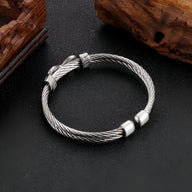 Bracelet jonc argenté en acier inoxydable tressé avec motif infini et fermoir métallique lisse.