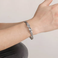 Bracelet jonc en acier inoxydable argent avec motif infini élégant porté au poignet.