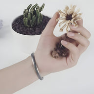 Bracelet jonc en acier inoxydable argenté avec motif notes de musique, style mixte, porté au poignet.