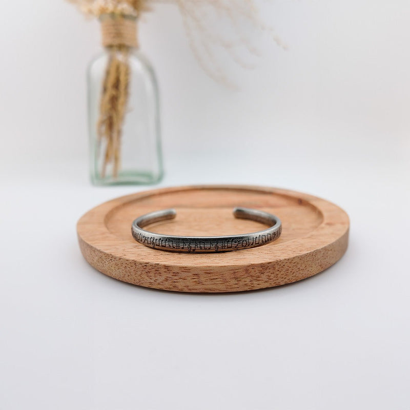 Bracelet jonc en acier inoxydable brossé avec gravures de notes de musique, finition argentée, modèle unisexe Suad.