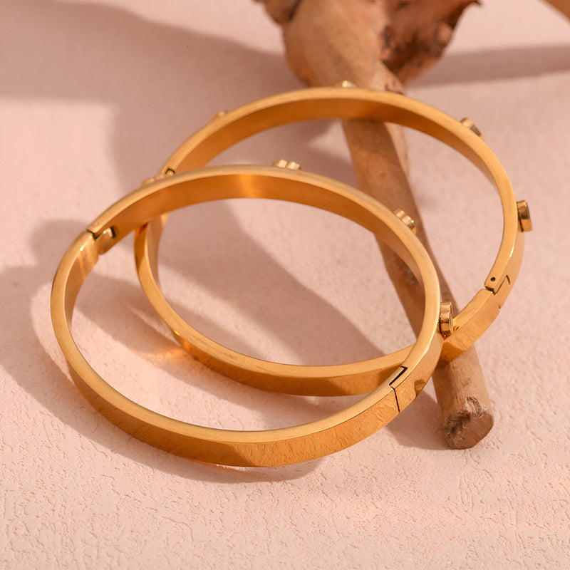 Bracelet jonc rond en acier inoxydable plaqué or 18 carats avec petits coeurs gravés, modèle Venus.