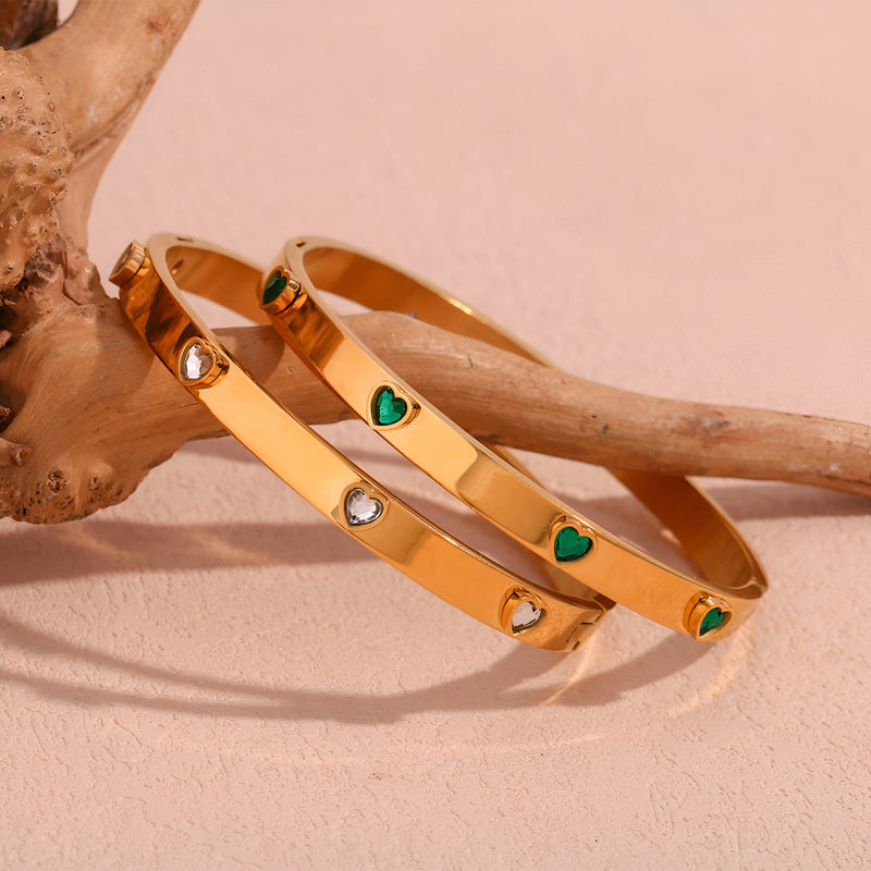 Bracelet jonc en acier doré 18 carats orné de cœurs verts et de diamants blancs.