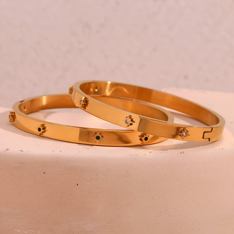 Bracelet jonc en acier doré 18 carats avec étoiles gravées et petit fermoir discret.