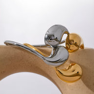 Bracelet jonc en acier inoxydable, finition argent et or, design minimaliste et incurvé.