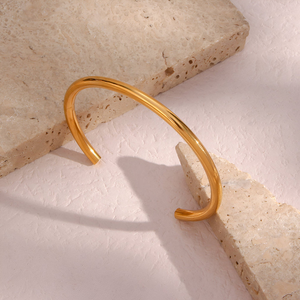 Bracelet jonc fin en acier inoxydable doré, finition lisse et brillante, style épuré féminin.