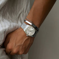 Bracelet jonc personnalisé en acier inoxydable argenté, porté avec montre vintage argentée à cadran blanc.