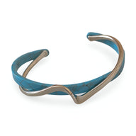 Bracelet jonc en acrylique bleu marine marbré avec détails en métal argenté ondulé.