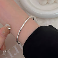 Bracelet jonc fin en argent sterling avec gravure "Smile" porté au poignet féminin.
