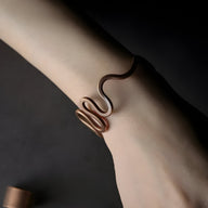 Bracelet jonc en cuivre marron forme grande vague sur poignet, style minimaliste et élégant.