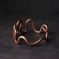 Bracelet jonc en cuivre à grande vague, finition mate, style minimaliste et moderne.