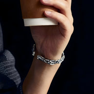 Bracelet jonc argenté en cuivre avec motif ondulé pour homme porté au poignet.