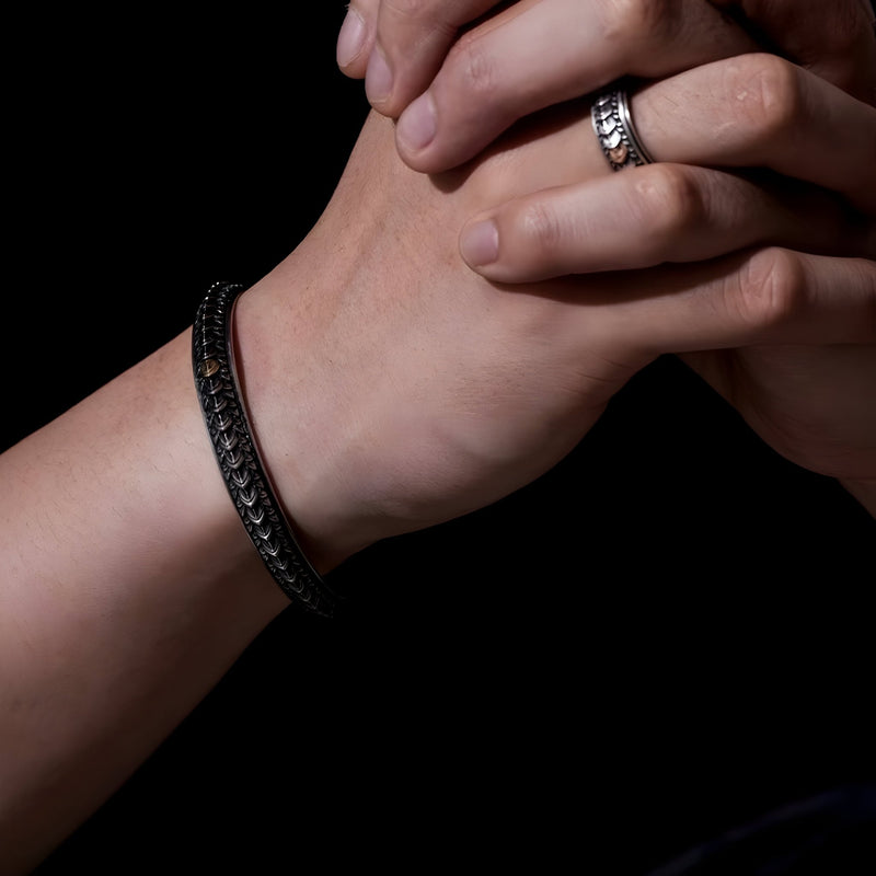 Bracelet jonc en cuivre argenté avec motif écailles de dragon texturé porté au poignet homme.