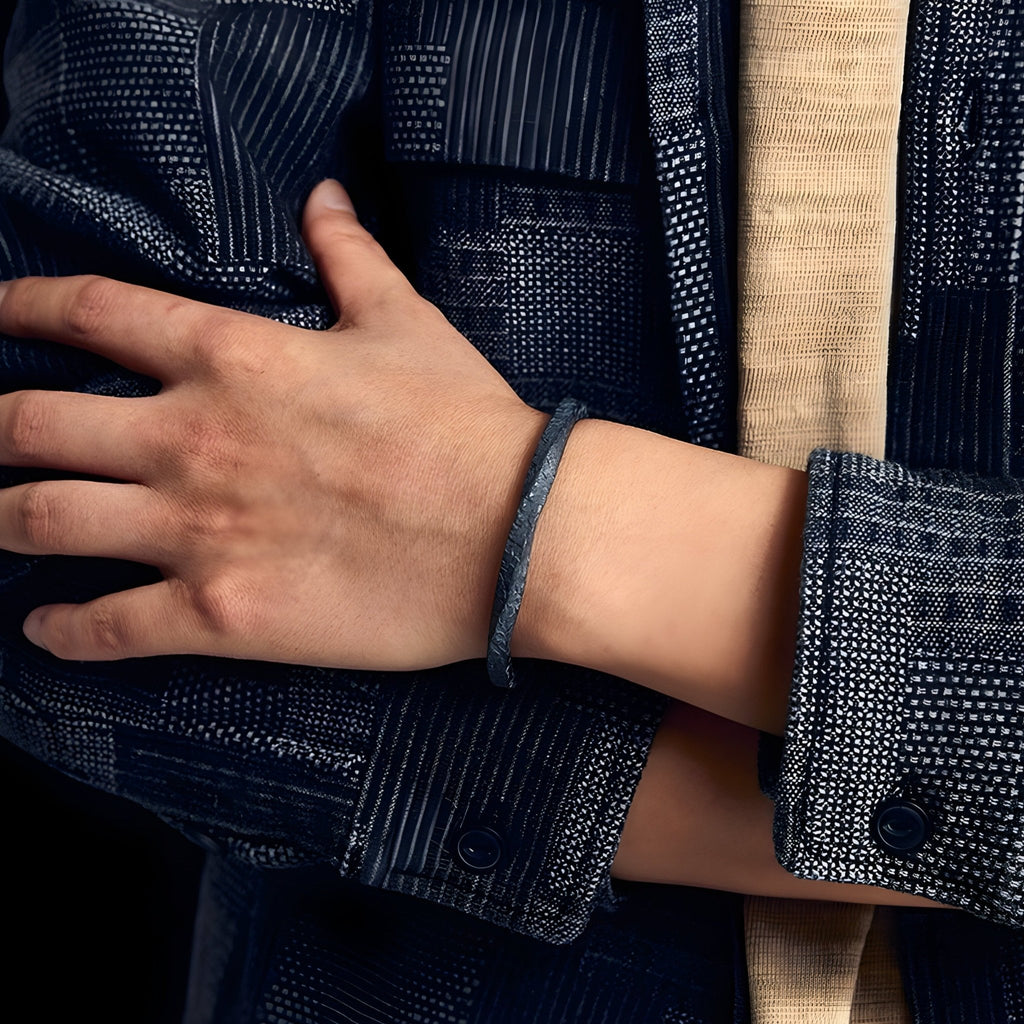 Bracelet jonc gris en cuivre plaqué argent et or, texture rocheuse, style masculin élégant.