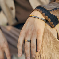 Bracelet jonc en cuivre plaqué argent et or effet rocheux gris porté au poignet masculin.