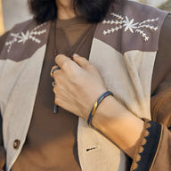 Bracelet jonc en cuivre gris avec plaquage argent et or, style rocheux, porté au poignet homme.