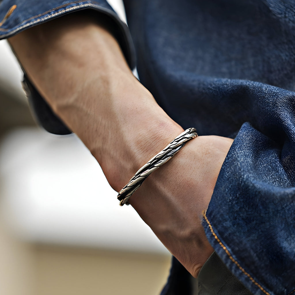 Bracelet jonc en cuivre plaqué argent torsadé, style masculin, porté au poignet avec manche en jean bleu.