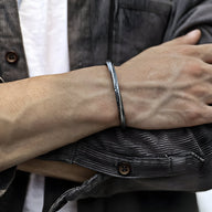 Bracelet jonc fin en cuivre plaqué argent, style viking, porté sur poignet masculin.