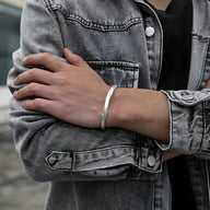 Bracelet jonc argenté en cuivre avec texture martelée, style viking masculin, porté au poignet.