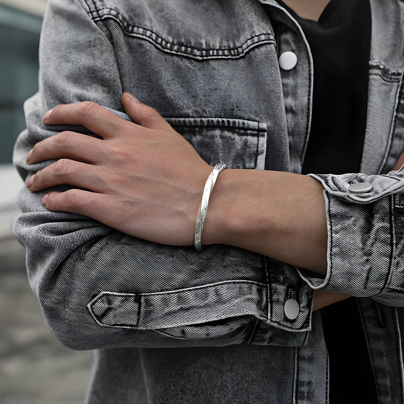 Bracelet jonc argenté en cuivre avec texture martelée, style viking masculin, porté au poignet.