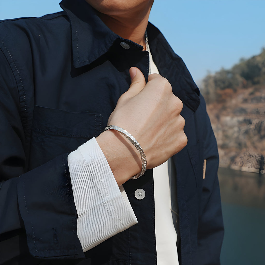 Bracelet jonc argenté en cuivre plaqué avec motifs flèche, porté homme, finition lisse et brillante.