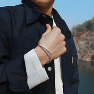 Bracelet jonc argenté en cuivre plaqué avec motifs flèche, porté homme, finition lisse et brillante.