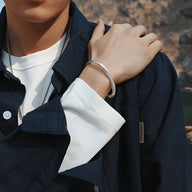 Bracelet jonc gris en cuivre plaqué argent avec motifs flèche porté au poignet masculin.