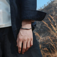 Bracelet jonc gris en cuivre plaqué argent avec motifs flèche porté au poignet homme.