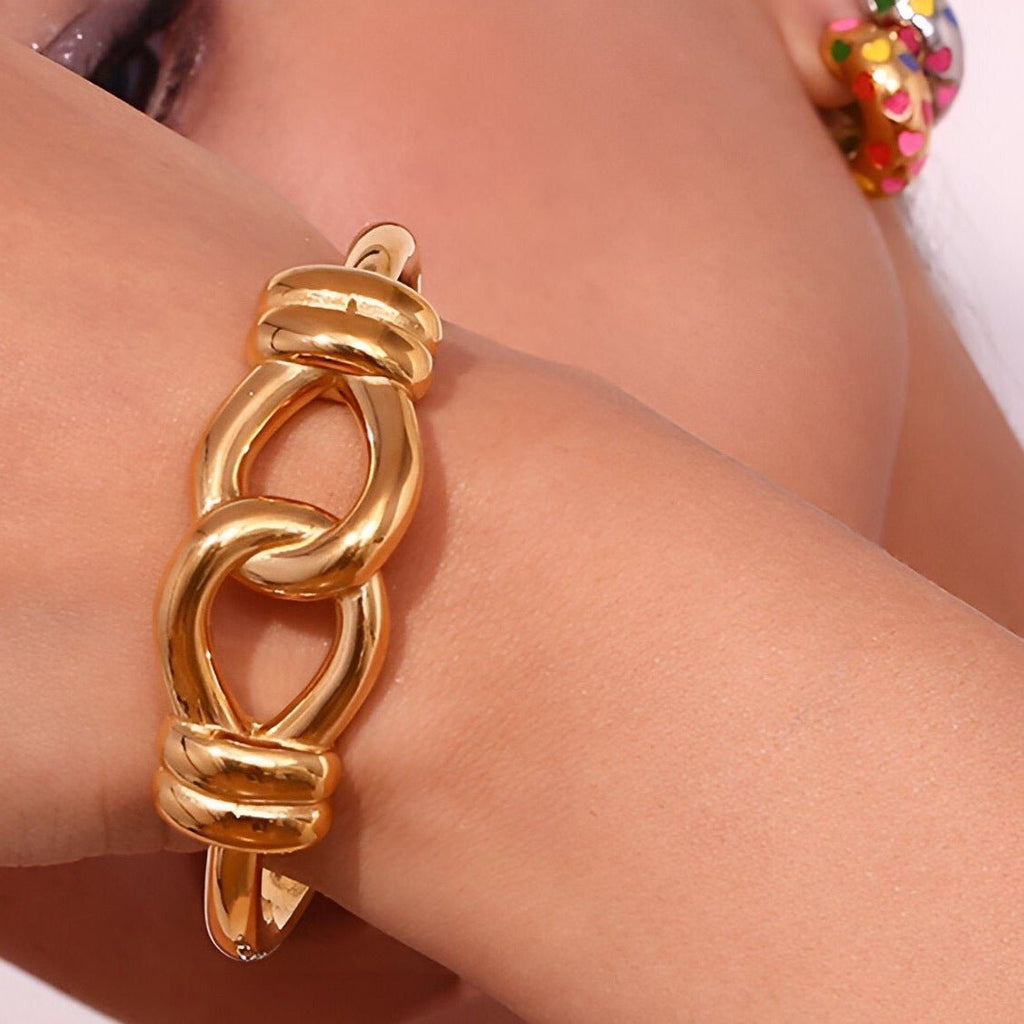 Bracelet jonc doré en acier inoxydable avec design en noeud d'agui épais et lisse.