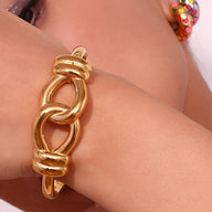 Bracelet jonc doré en acier inoxydable avec design en noeud d'agui épais et lisse.