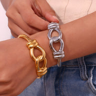 Bracelet jonc en acier inoxydable argenté modèle Cassiopée à motif nœud d'agui, porté au poignet Bracelet jonc en acier.